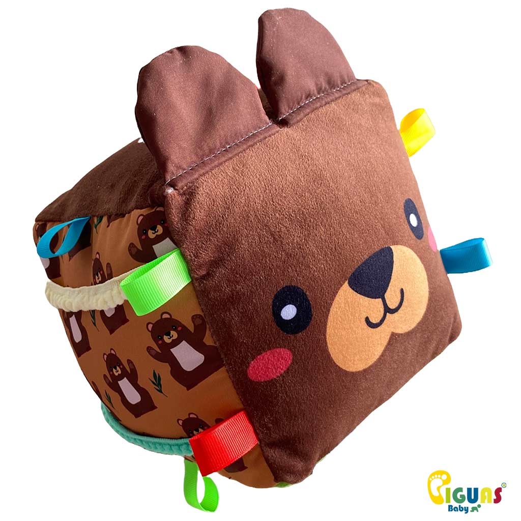 Un cubo sensorial para bebés con la cara de una osito curioso, con texturas suaves y llamativas, perfecto para estimular el tacto y la vista de tu pequeño