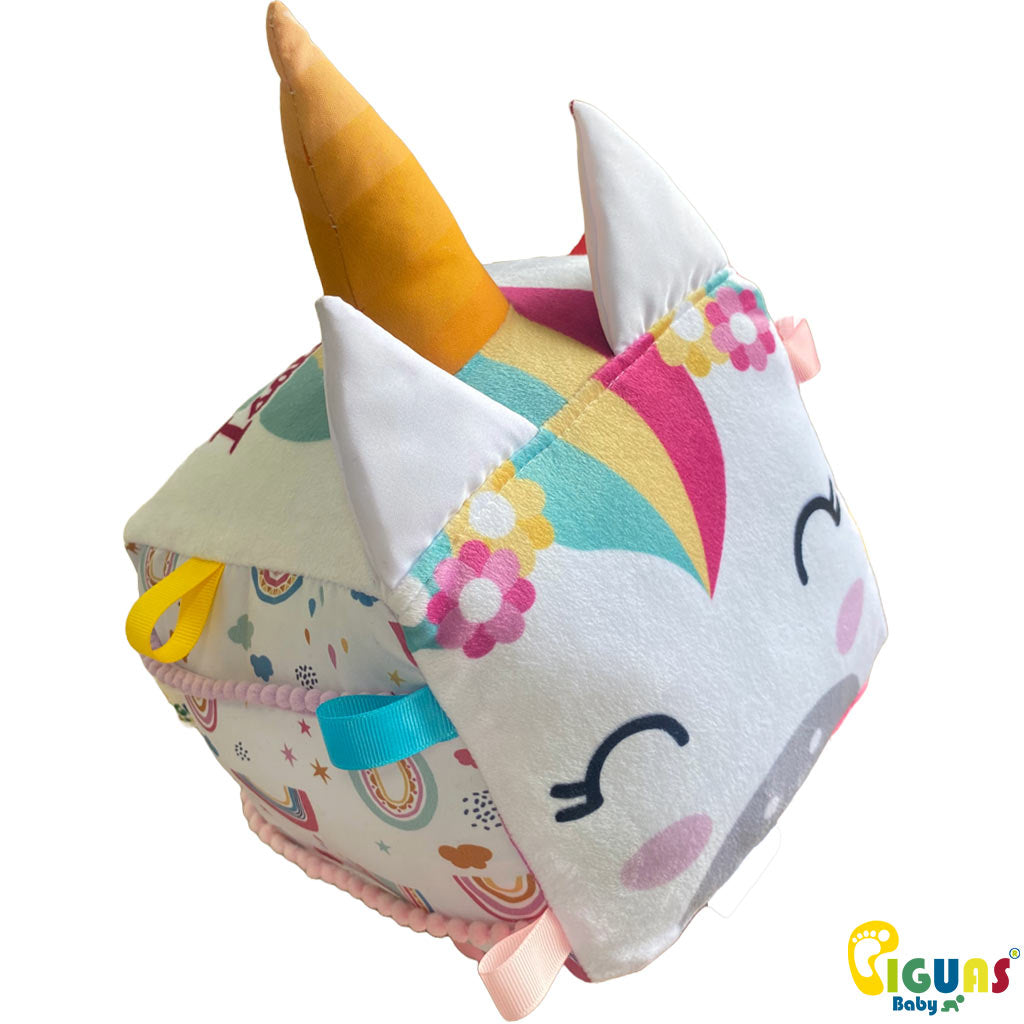 Un cubo sensorial para bebés con la cara de un unicornio curioso, con texturas suaves y llamativas, perfecto para estimular el tacto y la vista de tu pequeño
