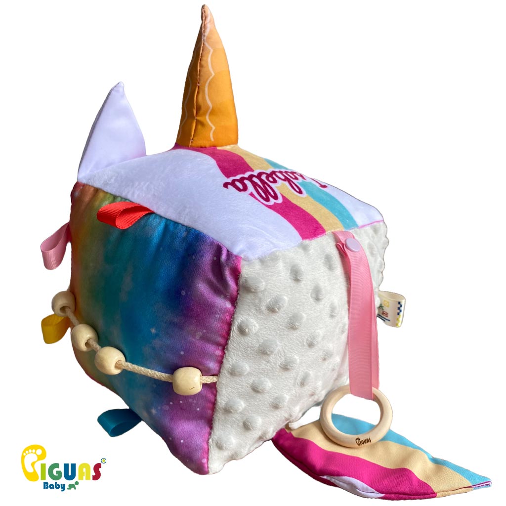 Cubo sensorial con la cara del unicornio mas inteligente que emite sonidos al agitarlo, al ser sonajero, y al agarrar sus orejas, al estar hechas con papel crujiente, ideal para el desarrollo auditivo del bebé.