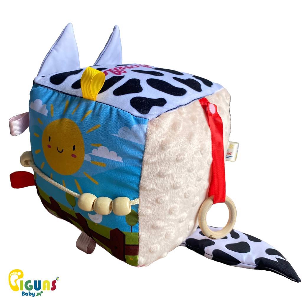 Cubo sensorial con la cara de la vaca mas inteligente que emite sonidos al agitarlo, al ser sonajero, y al agarrar sus orejas, al estar hechas con papel crujiente, ideal para el desarrollo auditivo del bebé.