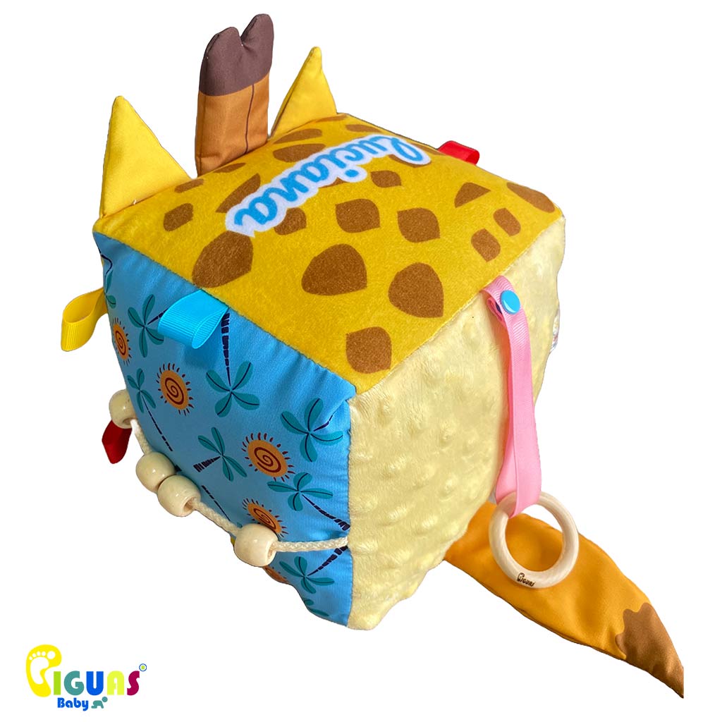 Cubo sensorial con forma cara de la jirafa más inteligente que emite sonidos al agitarlo, al ser sonajero, y al agarrar sus orejas, al estar hechas con papel crujiente, ideal para el desarrollo auditivo del bebé. 