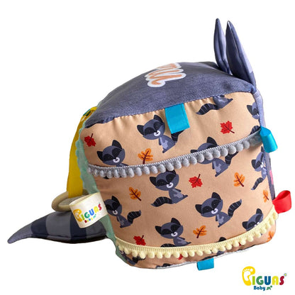 Un cubo sensorial para bebés con la cara de una mapache aventurero, perfecto para estimular la vista, la audición y el tacto de tu bebé